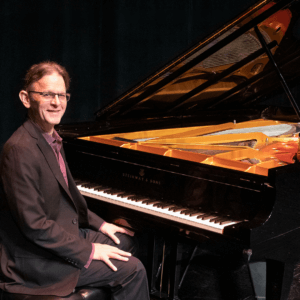 Dave Marck sits at a grand piano