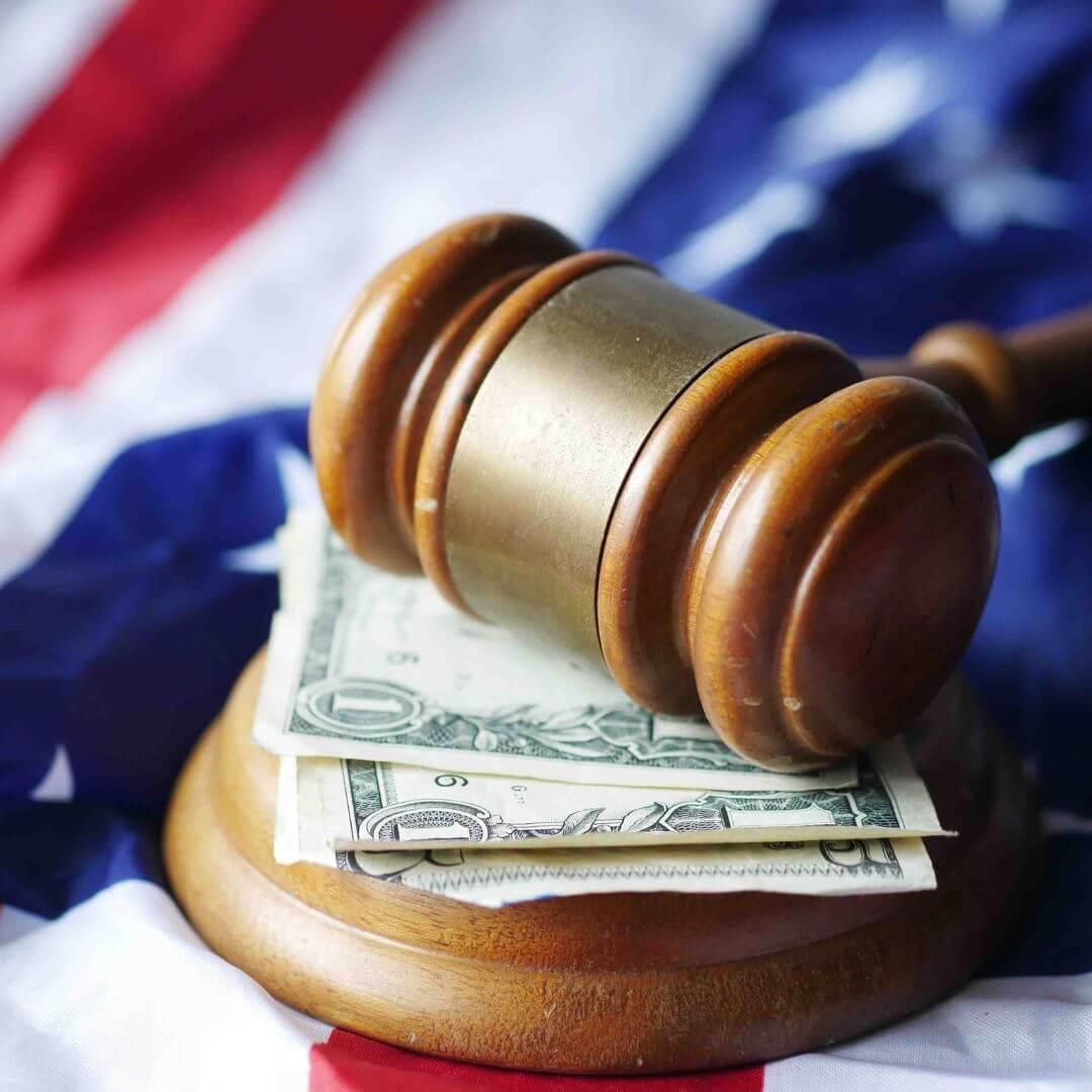 Legal gavel rests on dollars atop U.S. flag.