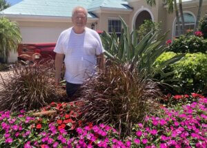 Al Wieser stands among flowers in his yard
