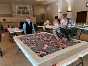 Pastor-Mark-Kvale-of-English-Lutheran-Church-ties-quilts-with-the-churchs-quilting-group.-The-quilts-are-distributed-throughout-the-world